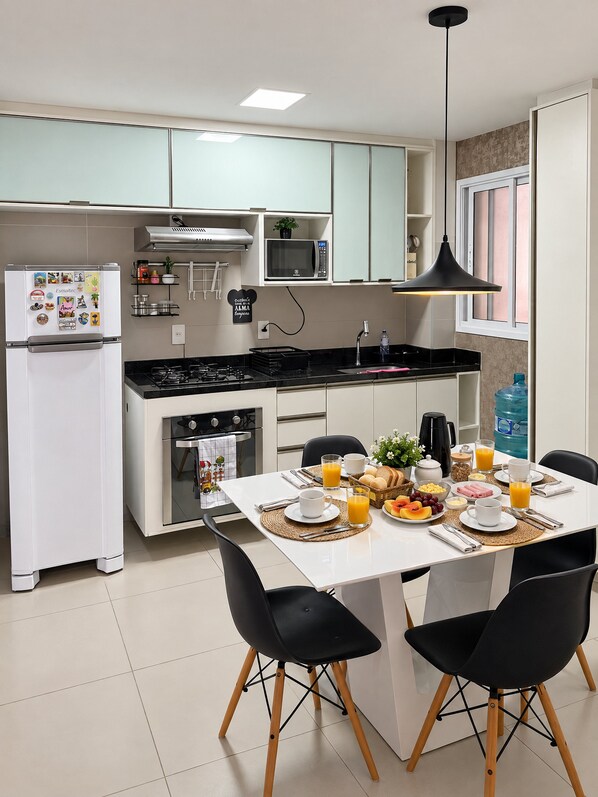 A modern kitchen with white cabinets, a microwave, a stove, and a dining area with a table set for breakfast.