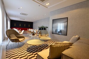 Un salon moderne avec un sol à carreaux, un grand canapé, des fauteuils et une table basse.