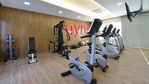 A gym with exercise equipment, a wall-mounted air conditioning unit, and a wooden floor. - Flat 2 Quartos a 50m da Praia Perto da Feirinha (Fortaleza)