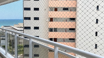 A balcony with a chain-link fence, overlooking a building with multiple floors and windows.