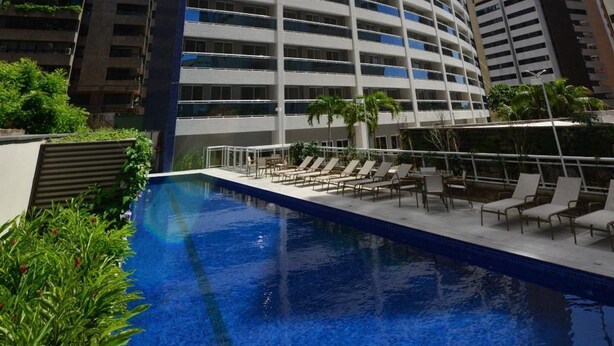 A high-rise hotel with a swimming pool and lounge chairs. - Flat 2 Quartos a 50m da Praia Perto da Feirinha (Fortaleza)