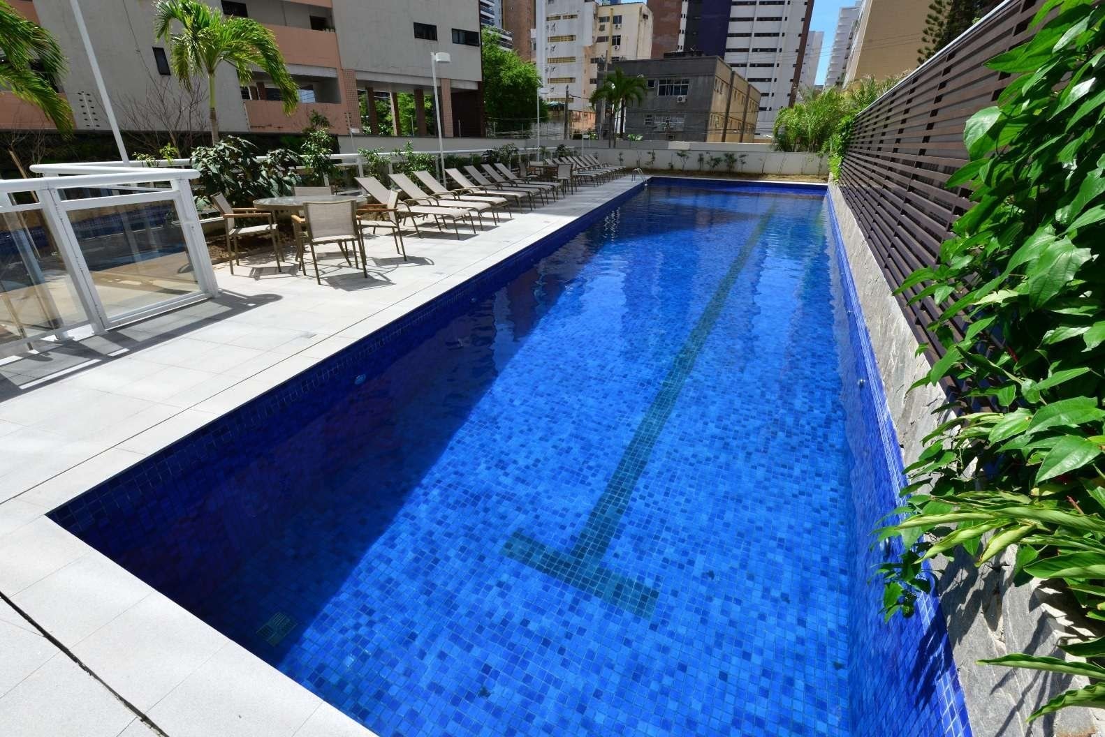 A swimming pool with lounge chairs and a glass railing.