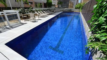 A swimming pool with lounge chairs and a glass railing.