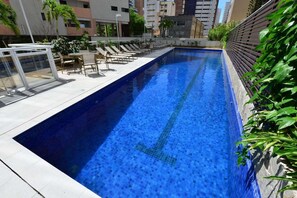 A swimming pool with lounge chairs and a glass railing.