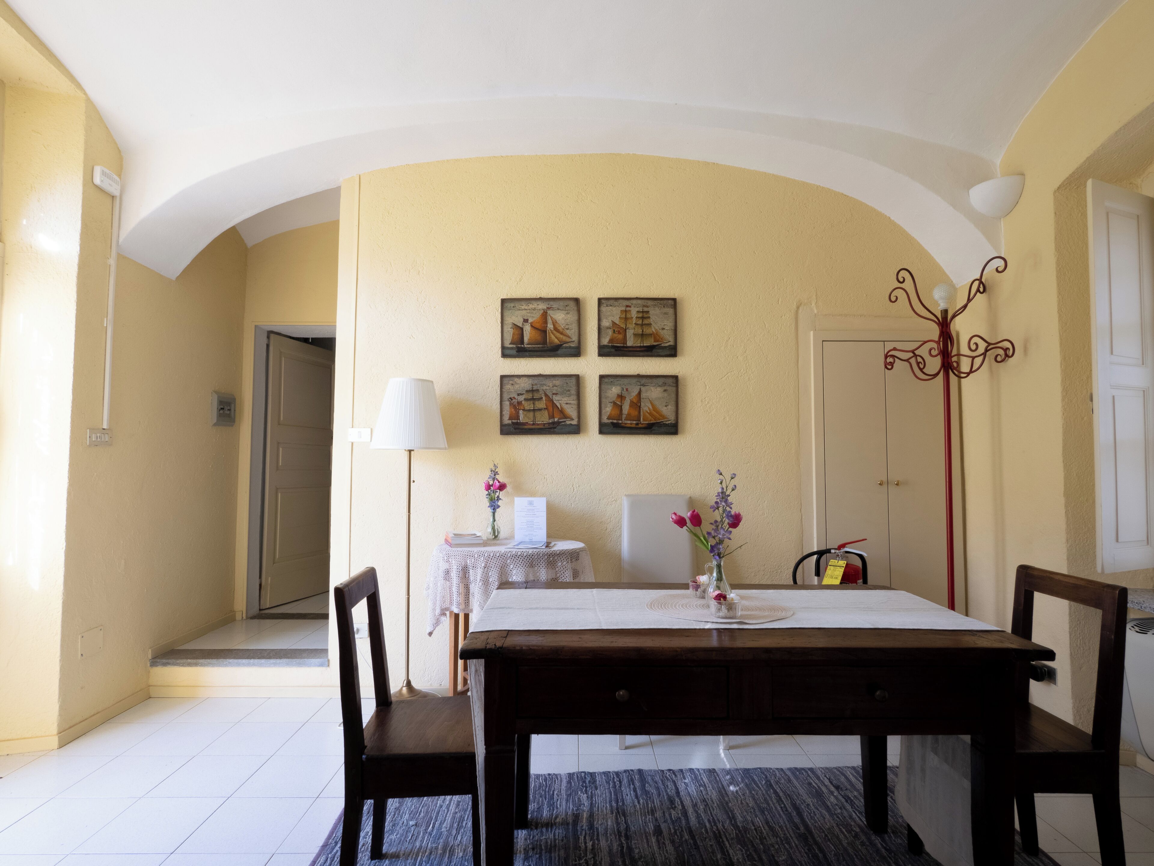 Un comedor con una mesa, sillas, una lámpara y cuadros en la pared.