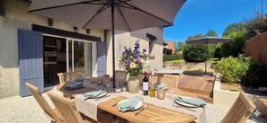 Ein Außenbereich zum Essen mit Holztischen, Stühlen und einem großen Sonnenschirm.