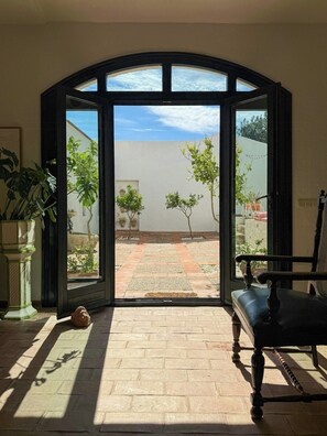 Eine offene Tür zu einer Terrasse mit Fliesenboden, einem Blumentopf und einem Stuhl.