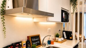 Une cuisine moderne équipée d’une hotte en acier inoxydable, d’un four à micro-ondes et d’une machine à café.