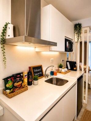 Een moderne keuken met een roestvrijstalen afzuigkap, een magnetron en een koffieapparaat.