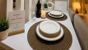 Un coin repas aménagé avec soin, agrémenté d’une pancarte accueillant les invités, d’une bouteille de vin, de verres et d’une bougie sur la table.