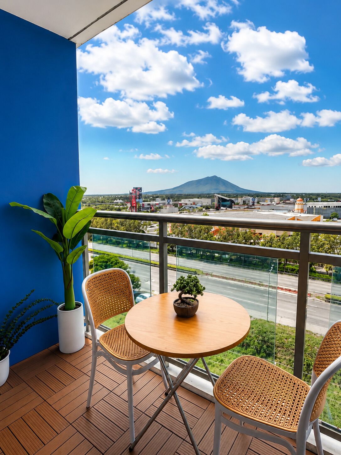 A balcony with a view of a mountain, a table with chairs, and potted plants.