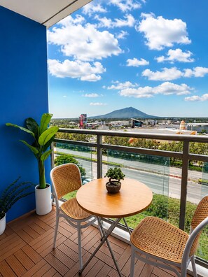 A balcony with a view of a mountain, a table with chairs, and potted plants.