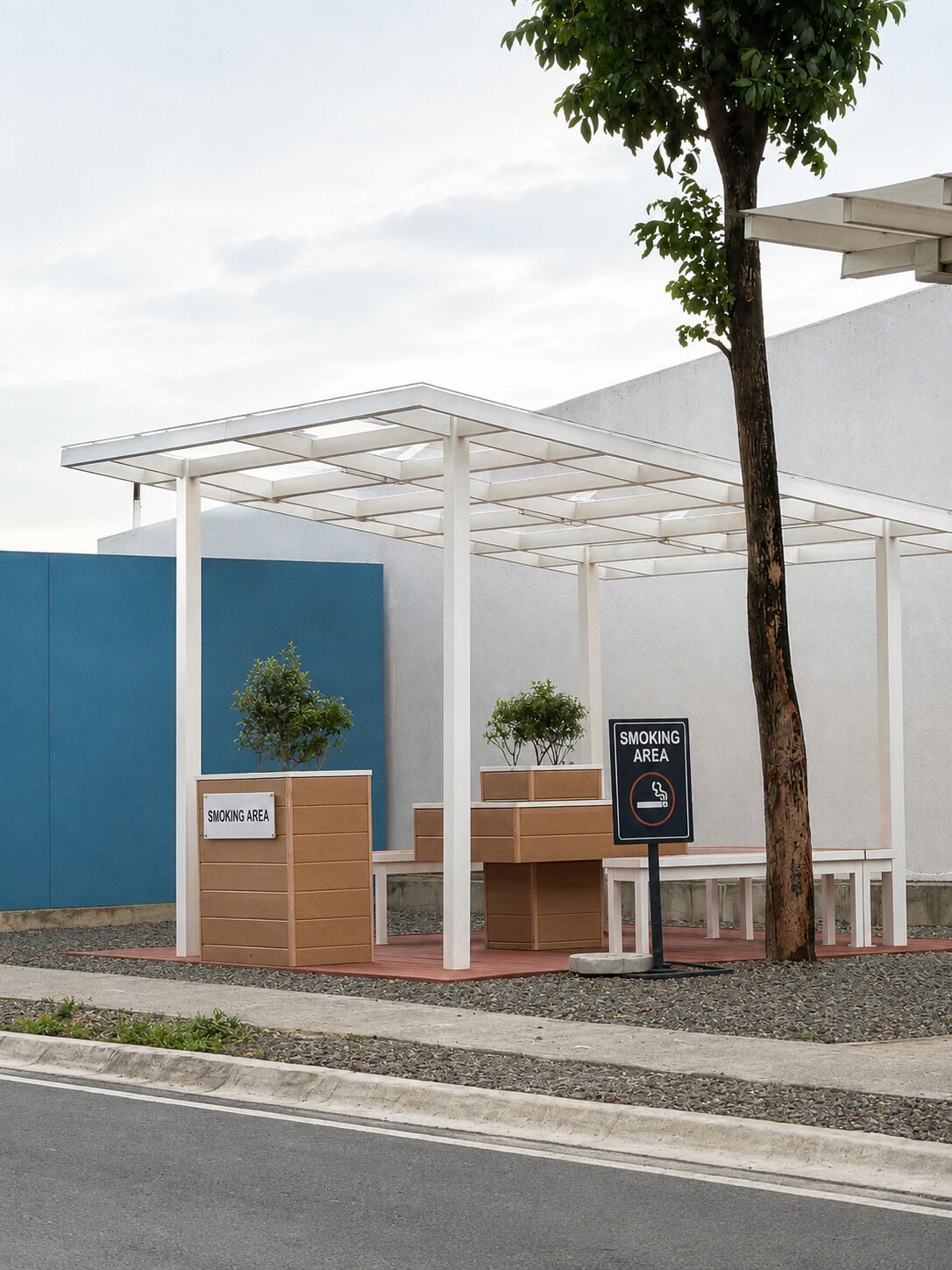 A covered outdoor seating area with a 'Smoking Area' sign, benches, and a tree.