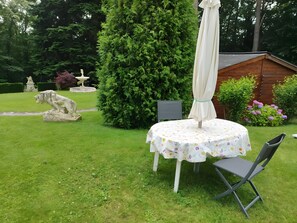 A garden with a round table, a chair, a statue, and a wooden structure. - Le Schaentzel, near Haut-Koenigsbourg Castle (Rodern)