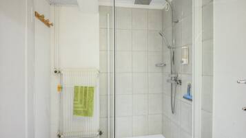 Een badkamer met een douche, toilet en een handdoekradiator.