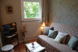Ein gemütliches Zimmer mit Bett, Fernseher, kleinem Tisch und Fenster.