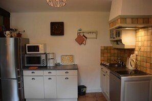 Cocina compacta equipada con refrigerador, microondas, cafetera y tostadora pequeña.