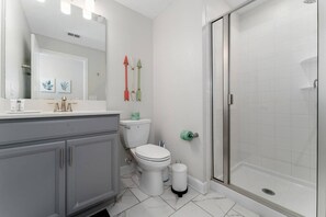 Ein Badezimmer mit Toilette, Waschbecken, Spiegel und Dusche.