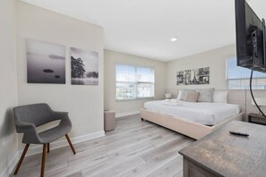 Ein Schlafzimmer mit einem Bett, einem Sessel, einem Fernseher und Bildern an den Wänden.