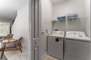 Een wasserette met een wasmachine, droger en planken met opgevouwen handdoeken.