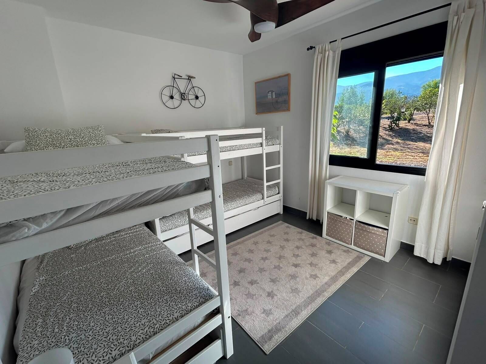 A bunk bed room with a desk and a window with a view.