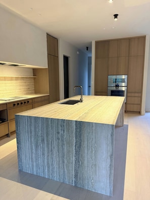 Een moderne keuken met een centraal eiland, roestvrijstalen apparatuur en houten kastjes.