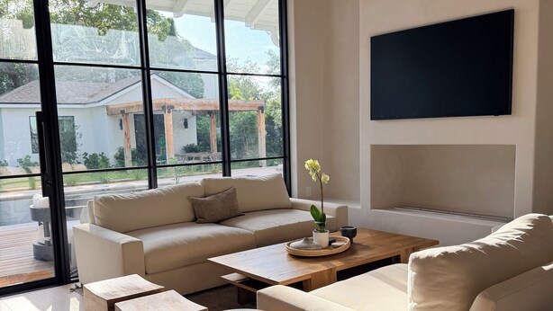 A modern living room with a large sliding glass door, a flat-screen TV mounted on the wall, and a wooden coffee table. - Bali-inspired Oasis in the Heart of Winter Park (Winter Park)