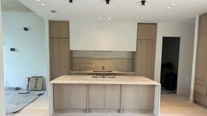 A modern kitchen with a central island, light wood cabinetry, and recessed ceiling lights. - Bali-inspired Oasis in the Heart of Winter Park (Winter Park)