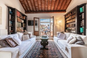Ein Wohnzimmer mit zwei weißen Sofas, einem Couchtisch und Bücherregalen voller Bücher.