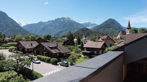 A residential area with houses, a church, and mountains in the background. - Charming Alpine Apt with View, 5min to Interlaken Ost (Interlaken)