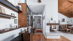 A modern interior with a wooden floor, a dining area with chairs, a TV, and shelves with various items. - Charming Alpine Apt with View, 5min to Interlaken Ost (Interlaken)