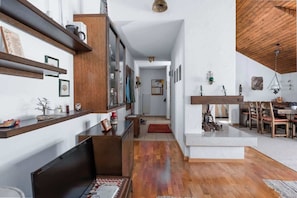 A modern interior with a wooden floor, a dining area with chairs, a TV, and shelves with various items. - Charming Alpine Apt with View, 5min to Interlaken Ost (Interlaken)