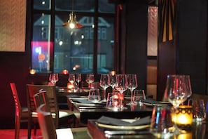 Ein Restaurant mit gedeckten Tischen, Blick aus dem Fenster und hängenden Pendelleuchten.