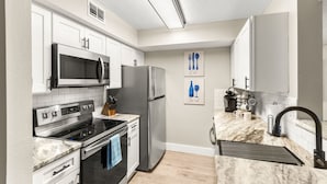 Een moderne keuken met witte kasten, roestvrijstalen apparatuur en een marmeren aanrecht.