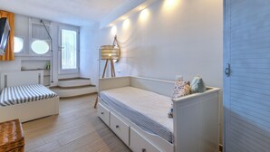 Ett sovrum med en säng, ett skrivbord, en stol, en lampa och ett fönster.