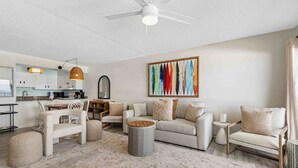 Ein modernes Wohnzimmer mit Sofa, Sesseln, Couchtisch und einer Essecke mit Tisch und Stühlen.