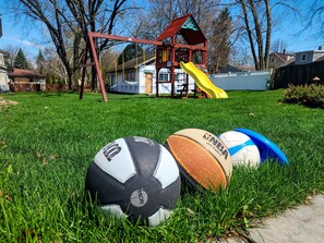 A grassy area with a swing set, a slide, and a playhouse in the background. - Game Night Haven with Gas Fireplace (Oak Creek)