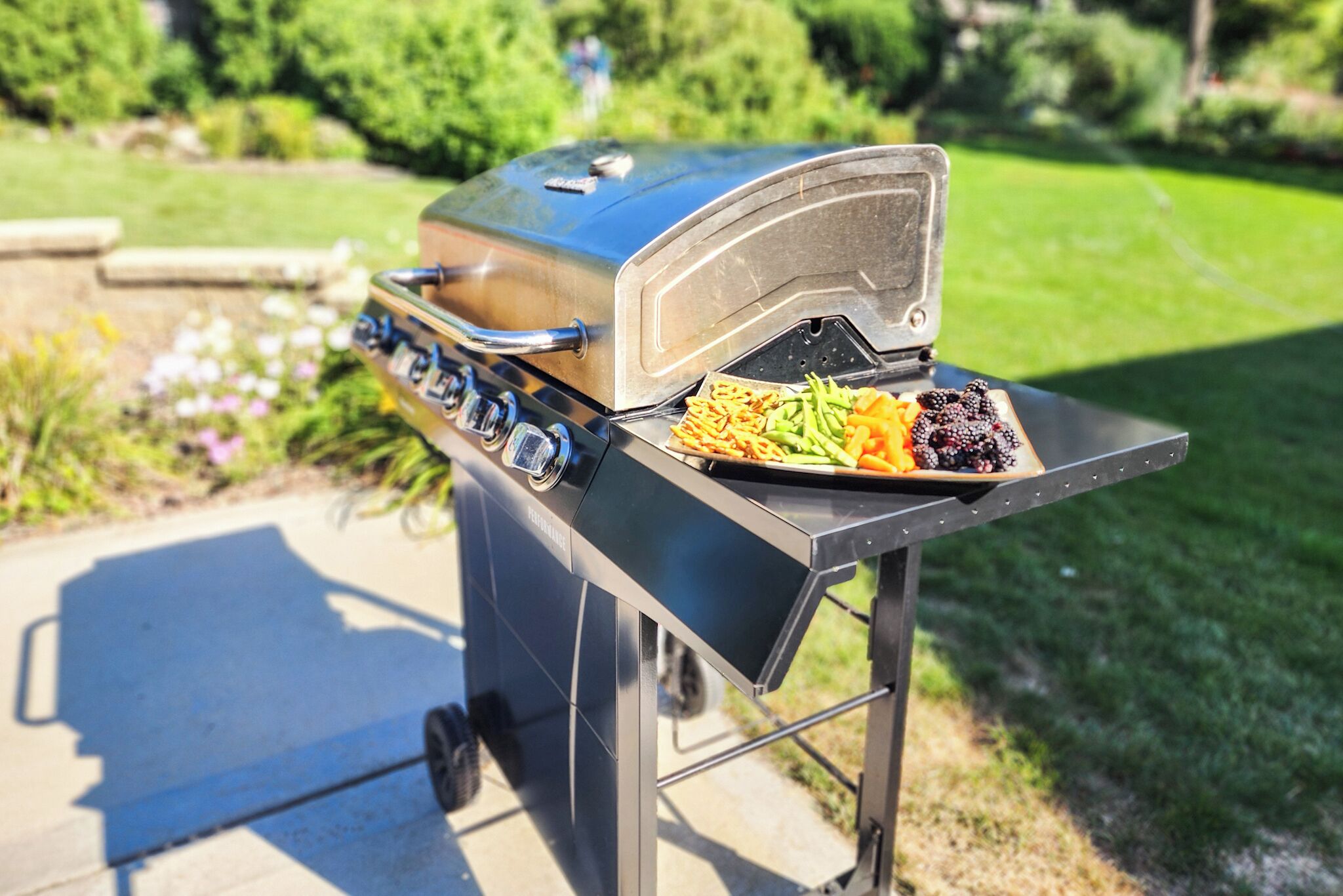 En portabel grill med ett öppet lock, där man kan se matvaror som grönsaker och kött.