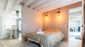 Een slaapkamer met een bed, nachtkastje en een badkamer met een wastafel.