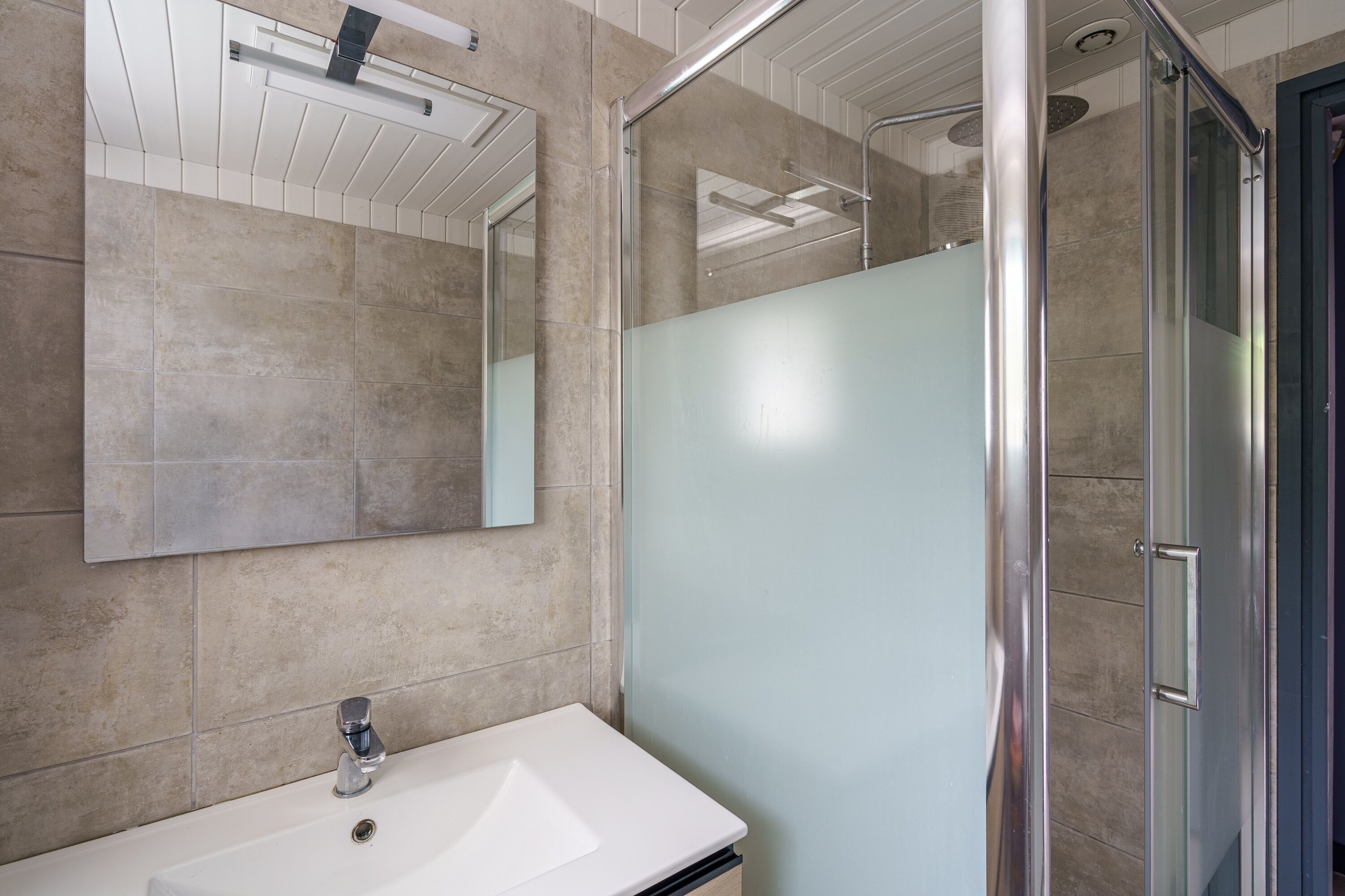 A bathroom with a white sink, a mirror, and a glass shower enclosure.