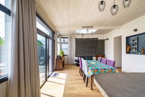 Ein modernes Interieur mit Essbereich, einer Couch und einem großen Fenster mit Vorhängen.