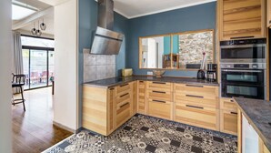 Una cocina moderna con armarios de madera, una campana extractora de acero inoxidable y un piso de baldosas con diseño.