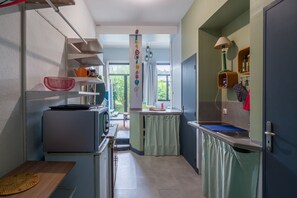 Eine kleine Küche mit Kühlschrank, Spüle und Regalen.