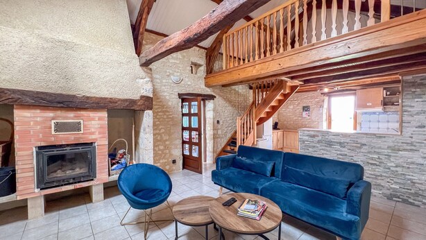 Un interior rústico con chimenea, muebles azules y una escalera de madera.