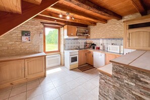 A kitchen with wooden cabinets, a stove, and a tiled backsplash. - Le Clos de Rouffiac - Maison pour 7 avec jardin (Carnac-Rouffiac)