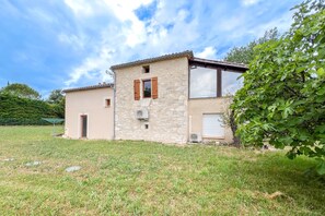 A two-story stone house with a flat roof, a small attached garage, and a grassy yard. - Le Clos de Rouffiac - Maison pour 7 avec jardin (Carnac-Rouffiac)