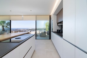 A modern kitchen with a view of the city, a dining area, and a balcony with a view. - Penthouse with Panoramic Sea Views in Estepona (Estepona)