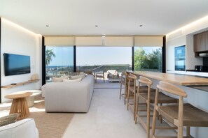 A modern interior with a sofa, dining area, kitchen, and large windows offering a view. - Penthouse with Panoramic Sea Views in Estepona (Estepona)