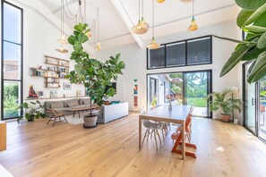 Un vaste espace de vie comprenant une table à manger, un canapé et une bibliothèque.