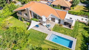 Una casa moderna con piscina, patio y césped bien cuidado.